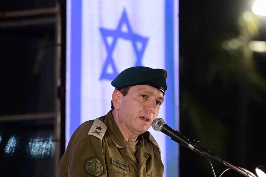 Military officer speaking at a microphone in front of an Israeli flag - rapture second coming